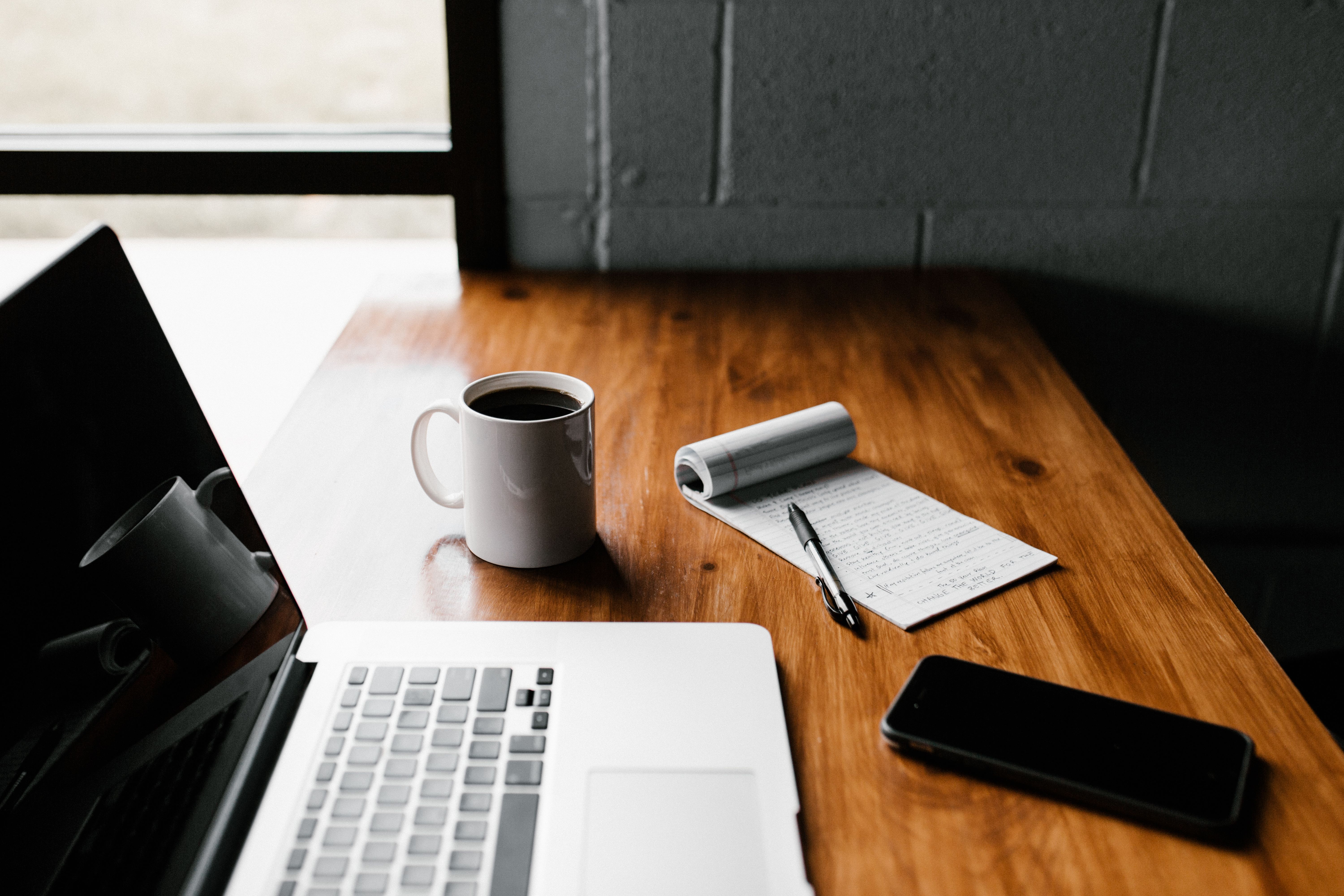 Laptop, notebook, phone, and coffee arranged for a consultation